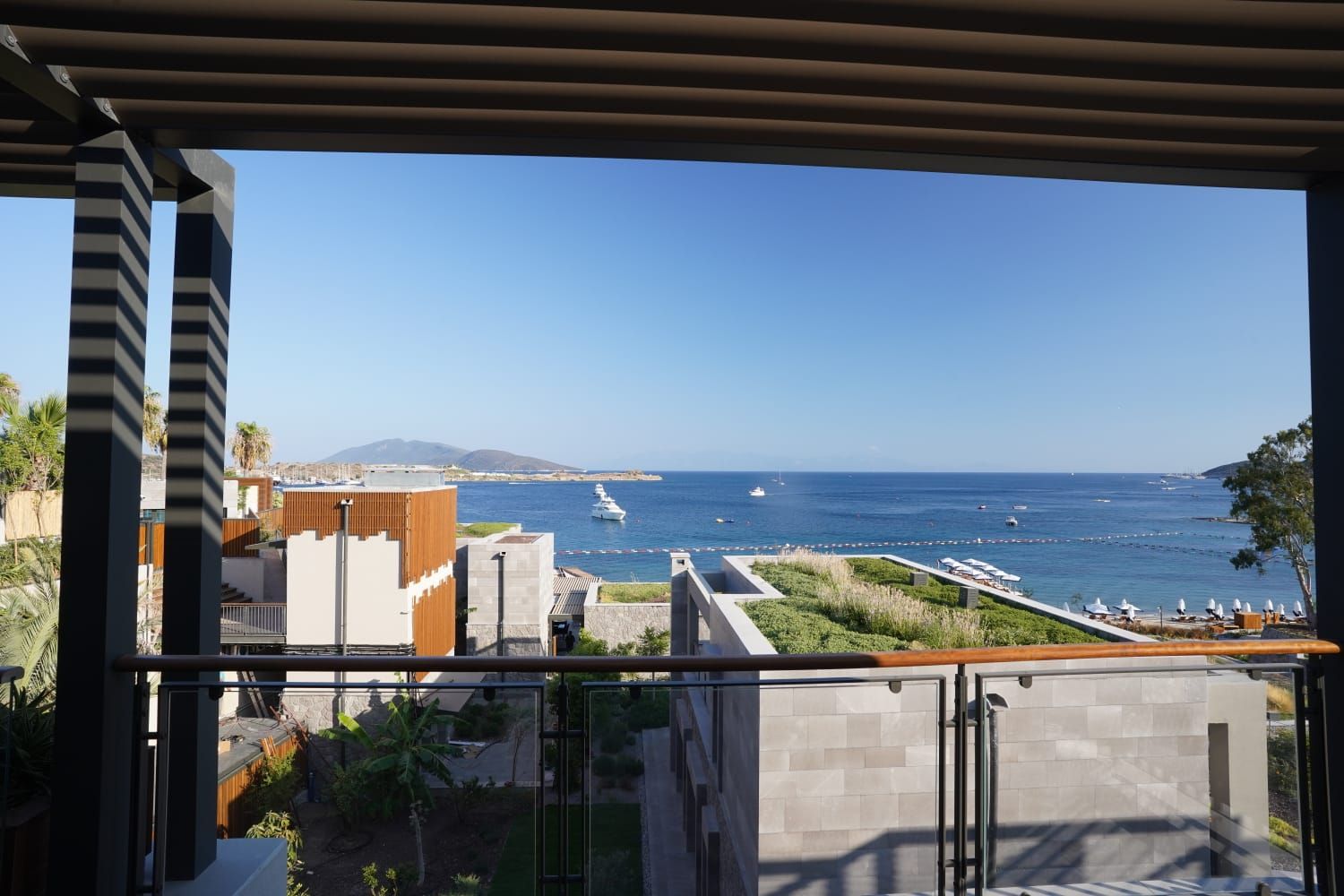 Pergola çerçevesinden yeşil çatılar ve deniz